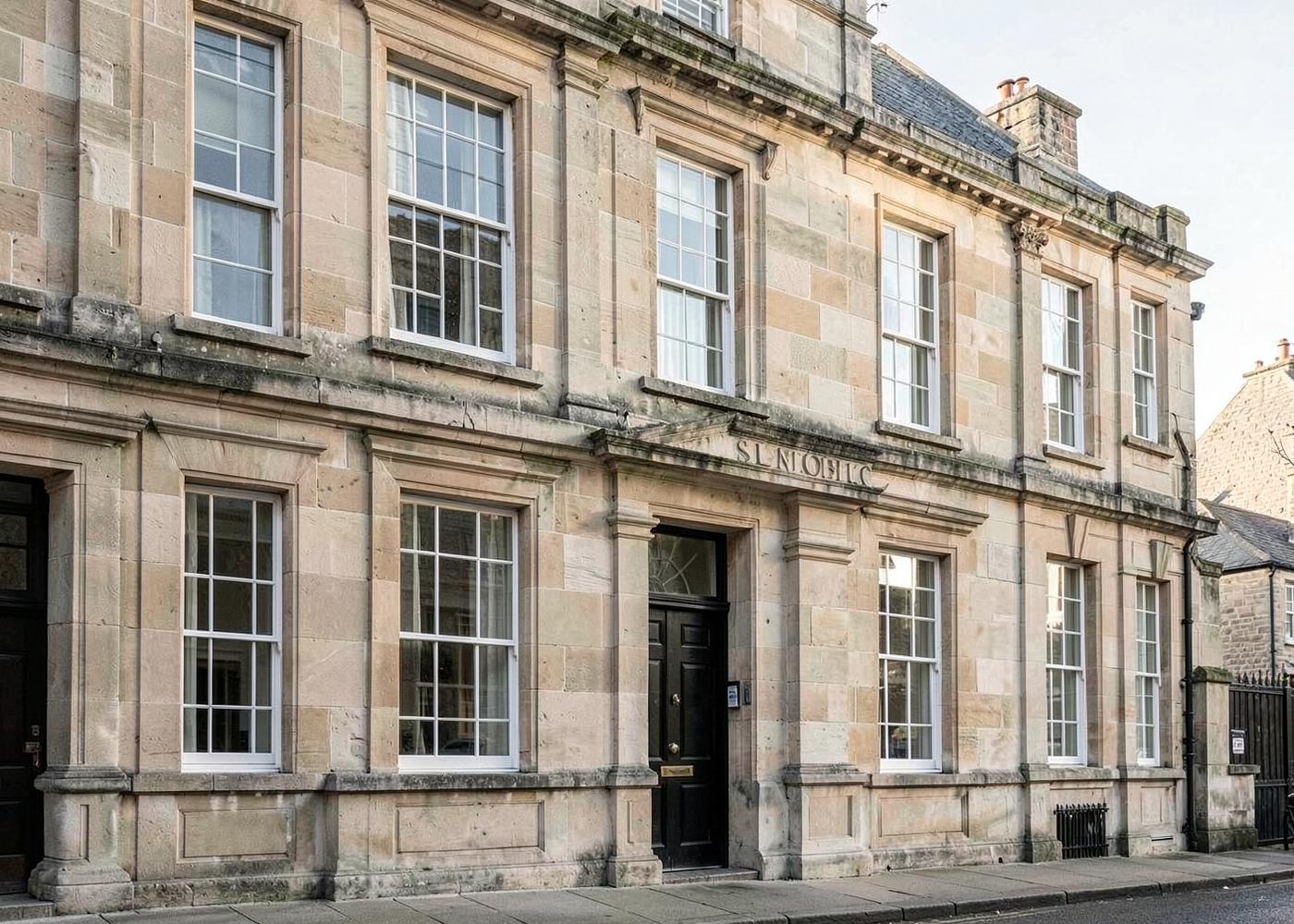 A classic stone commercial building with tall sash windows in morning light